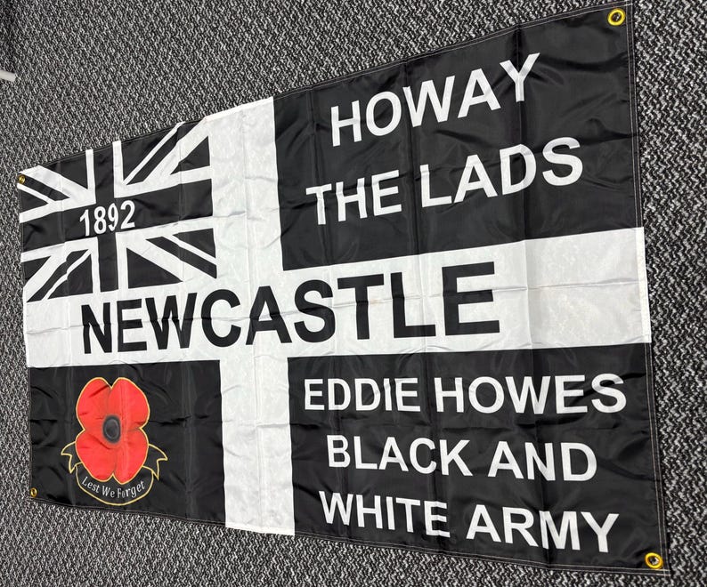 May include: Black and white flag with the text "HOWAY THE LADS NEWCASTLE EDDIE HOWES BLACK AND WHITE ARMY". Features a Union Jack design, the year 1892, and a red poppy with the words "Lest We Forget".