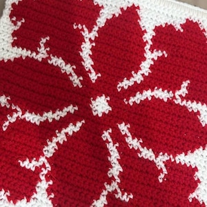 May include: A red and white crocheted flower design with a white border. The flower is in the center of the square.