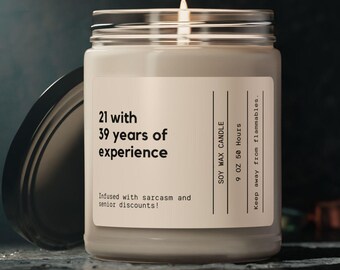 Può includere: Una candela di cera di soia beige con un'etichetta nera che recita "21 with 39 years of experience" e "Indused with sarcasm and senior discounts!" La candela è una candela da 9 oz con un tempo di combustione di 50 ore. L'etichetta riporta anche "Soy Max Candle" e "Keep away from flammables."