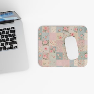 May include: A pink and blue floral mouse mat with a patchwork design. The mouse mat features a variety of pink roses and floral patterns.
