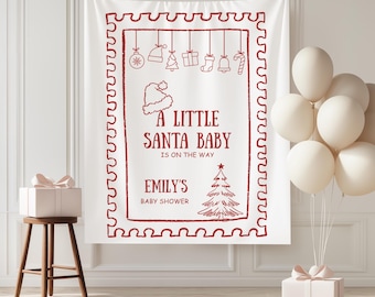 May include: A white fabric backdrop with a red border and text that reads "A Little Santa Baby Is On The Way." The backdrop features Christmas-themed illustrations and is decorated for a baby shower. White balloons and gift boxes are also present.