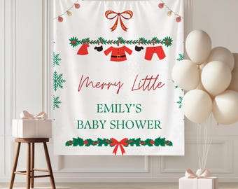 May include: A white baby shower banner with the text "Merry Little Emily's Baby Shower" in red and green. The banner features festive Christmas-themed illustrations, including baby clothes and snowflakes. A gift box and balloons are also present.