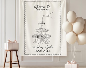 May include: A cream-colored wedding banner with a black line drawing of champagne glasses stacked in a pyramid. The banner reads "Cheers to forever!" and includes the names "Ashley & John" and the date "08.09.2025". White balloons and a gift box are also visible.