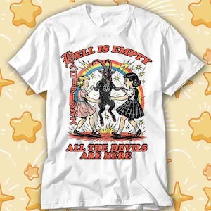 Puede incluir: Camiseta blanca con un diseño gráfico. El diseño presenta el texto "Hell is Empty, All the Devils Are Here", una cabra, dos chicas y un arcoíris. La camiseta tiene cuello redondo y mangas cortas.