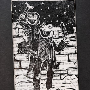 Puede incluir: Una ilustración en blanco y negro de dos personajes de "A Christmas Carol" caminando en la nieve. El personaje de la izquierda lleva un sombrero de copa y sostiene un bastón. El personaje de la derecha lleva un abrigo largo y sostiene un sombrero de copa.