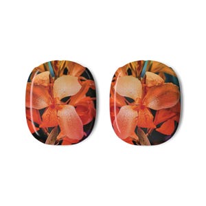 May include: Two oval-shaped nail art decals featuring a vibrant orange floral design. The flowers have a mix of orange and cream-colored petals with a dark background. The decals are set against a white background.