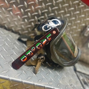 May include: A brown leather keychain with a green, white, and orange design that says "LOCAL FD" in a stylized font. The keychain is attached to a silver metal clip.