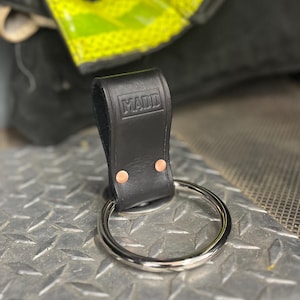 May include: Black leather fire hose holder with a metal ring and the word "MADD" embossed on the leather.