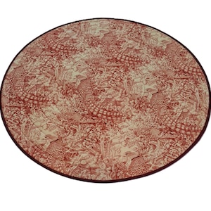 May include: A circular fabric mat featuring a repeating toile pattern in deep red on a cream background. The design depicts multiple pheasants surrounded by dense foliage, flowers, and branches. The mat has a dark red bound edge finish.