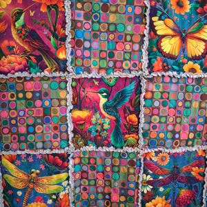 May include: A patchwork rag quilt featuring alternating squares of colorful floral patterns with hummingbirds, butterflies, and dragonflies, and squares with a multi-colored grid of circles. The seams have frayed, exposed fabric edges.