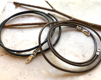 May include: Two leather cords with silver clasps. One cord is brown and the other is black.