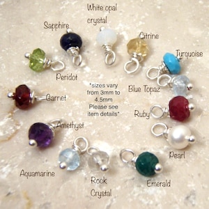 May include: A collection of gemstone charms, including sapphire, peridot, garnet, amethyst, aquamarine, rock crystal, emerald, pearl, ruby, blue topaz, citrine, turquoise, and white opal crystal. Each charm is attached to a silver-colored loop. Text on the image reads: "sizes vary from 3mm to 4.5mm. Please see item details."