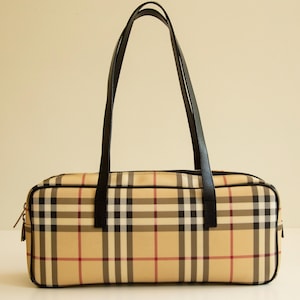 May include: A brown and beige plaid handbag with black handles. The bag has a rectangular shape and a zip closure.