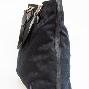 May include: Black tote bag with a repeating pattern of interlocking Gs. The bag features leather trim, gold-tone hardware, and a shoulder strap. The bag is made of a durable fabric.