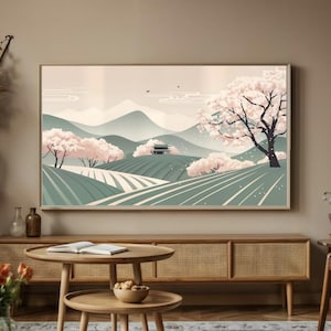 Pode incluir: Uma impressão emoldurada de uma paisagem estilizada com uma cordilheira, um pequeno edifício e árvores de cerejeira em flor em tons de rosa, verde e branco.