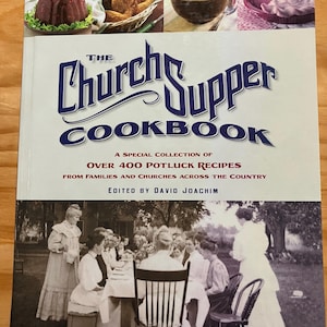 以下が含まれることがあります： 様々な料理の写真と、人々のセピア色の写真が表紙の「The Church Supper Cookbook」。タイトルは青色の筆記体。家族や教会からの400以上のポットラックレシピを収録しています。