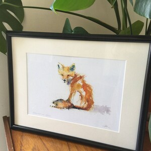May include: A watercolour painting of a fox sitting with its head turned to the side. The fox is painted in shades of orange, yellow, and white. The background is a light cream colour.