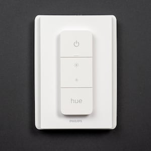 May include: A white Philips Hue smart light switch with a power button, two brightness buttons, and the word "hue" printed on it.