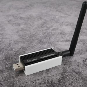 May include: A white and black USB wireless adapter with a black antenna. The adapter has the text "Sonoff" and "External 5dBi High Gain Antenna" printed on it.