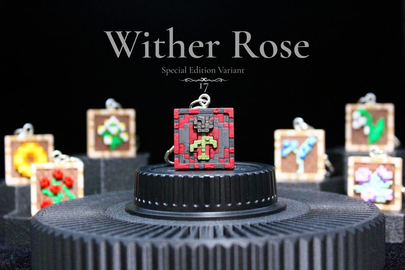 K&ouml;nnte beinhalten: Eine Sammlung pixeliger Anh&auml;nger, jeder mit einem anderen Blumendesign. Der zentrale Anh&auml;nger, mit der Aufschrift "Wither Rose", ist rot, grau und gr&uuml;n. Weitere Anh&auml;nger sind eine Sonnenblume, Rosen und andere Blumen.