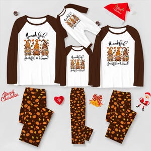 Peut inclure: Ensemble de pyjamas assortis pour la famille pour Thanksgiving. Chemises raglan blanches et marron avec le texte "thankful grateful & blessed" et des graphiques de gnomes. Pantalons assortis à motifs de citrouilles et un chapeau de Noël rouge.