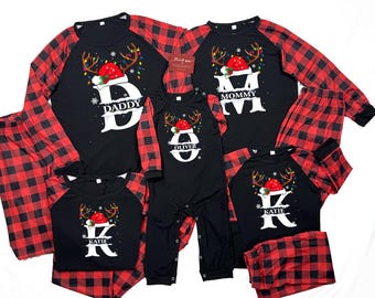 May include: Matching family Christmas pajamas in black and red buffalo plaid. Each pajama top features a Christmas design with a Santa hat and reindeer antlers. The pajamas are personalized with names and the word "Mommy" and "Daddy".