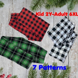 Könnte beinhalten: Drei Paar karierte Schlafanzughosen in Rot und Schwarz, Grün und Schwarz sowie Schwarz und Weiß. Der Text "Kid 2Y-Adult 6XL" und "7 Patterns" ist zu sehen. Die Hosen sind auf einem Holzgrund mit Kiefernzweigen gefaltet.