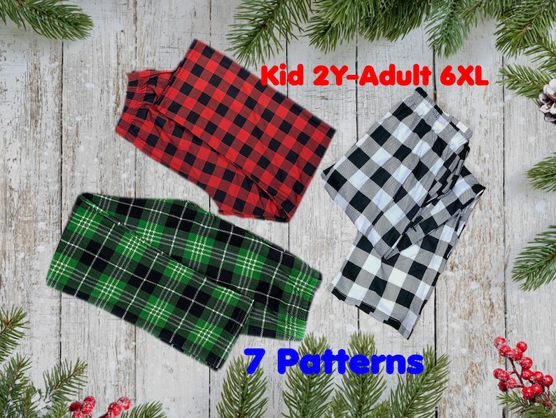 May include: Three pairs of plaid pajama pants in red and black, green and black, and black and white. The text "Kid 2Y-Adult 6XL" and "7 Patterns" are displayed. The pants are folded and arranged on a wooden background with pine branches.