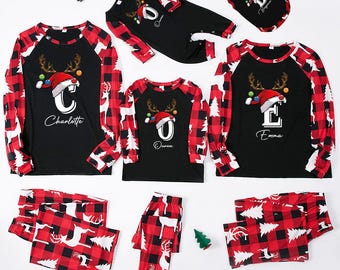 Può includere: Pigiama natalizio coordinato per la famiglia in fantasia scozzese nera e rossa. Le maglie sono nere con un design a renna e cappello di Babbo Natale, personalizzate con nomi. I pantaloni sono a quadri rossi. Include una tutina intera e una maglietta per cani.