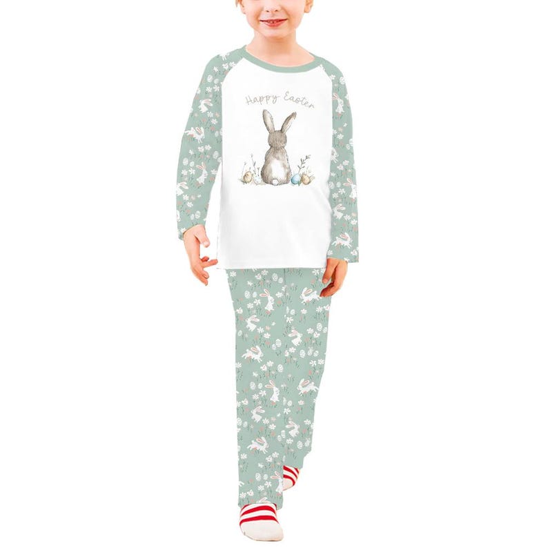 Pode incluir: Conjunto de pijama de duas pe&ccedil;as para crian&ccedil;as. A parte superior branca apresenta uma ilustra&ccedil;&atilde;o de coelho cinzento e o texto "Happy Easter". As mangas e as cal&ccedil;as s&atilde;o verde claro com um padr&atilde;o de coelhos e flores brancas.