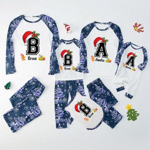 May include: Matching family Christmas pajamas. White tops with a letter, Santa hat, and name. Dark blue pants with Christmas tree pattern. Includes pajamas for adults, children, and a pet.