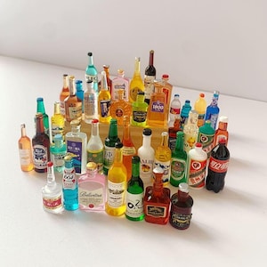 Puede incluir: Una colección de botellas de licor en miniatura de varias formas y colores. El surtido incluye botellas de vodka, vino y otros licores, con etiquetas visibles. Las botellas están dispuestas sobre una superficie clara.