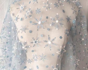 Light blue tulle mesh fabric with gold-foil snowflake and star pattern