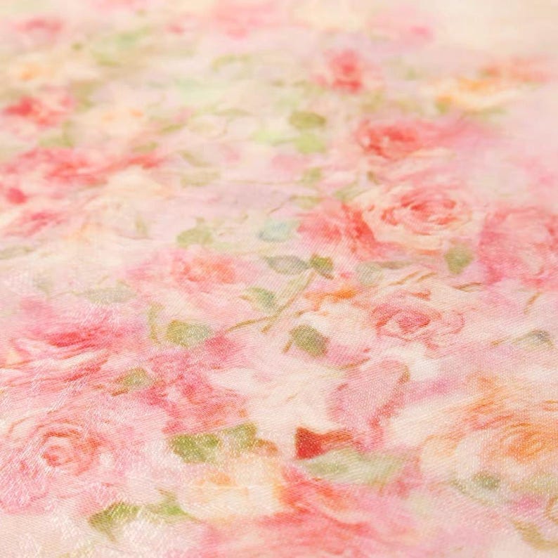Op de afbeelding: Close-up van een stof met een bloemenpatroon. Het ontwerp toont roze rozen en groene bladeren op een lichtroze achtergrond. De rozen vari&euml;ren in grootte en zijn dicht opeengepakt, wat een romantische en delicate esthetiek cre&euml;ert.