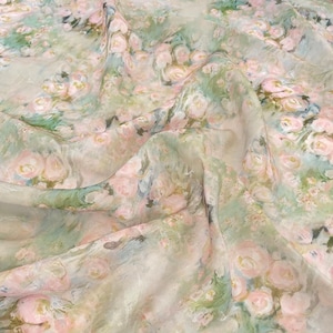 Puede incluir: Una tela ligera y transparente con un estampado floral impresionista de rosas de color rosa suave y follaje verde salvia. El material está drapeado para crear pliegues, resaltando la calidad translúcida y la paleta de colores mezclados.