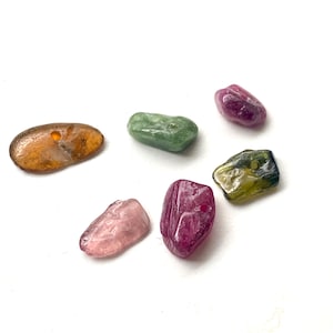Può includere: Sei perline di pietre preziose colorate con fori praticati. Le perline sono di varie tonalità di rosa, verde e marrone.
