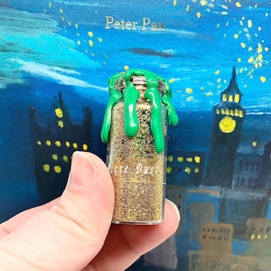 May include: A small glass jar filled with gold glitter and topped with green wax. The jar is labeled "Fairy Dust".