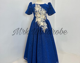 May include: A royal blue formal dress with a shimmering fabric. The dress features short sleeves and a full skirt. Gold floral embroidery adorns the bodice. The text "Mrk Wardrobe" is visible on the dress.