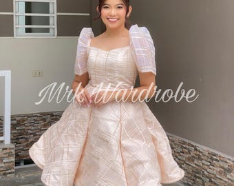 May include: A pale pink dress with a square neckline and puffed sleeves. The dress has a checkered pattern and a full skirt.