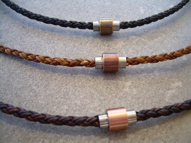 Peut inclure: Trois colliers en cuir tress&eacute; avec des accents de perles m&eacute;talliques. Les colliers sont en noir, marron et marron fonc&eacute;.