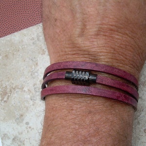 May include: A triple-wrap leather bracelet with a dark metal clasp. The bracelet is a deep burgundy color.
