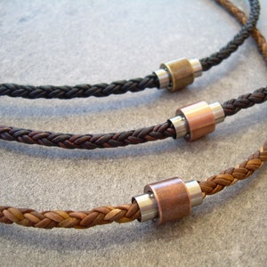 Peut inclure: Trois colliers en cuir tress&eacute; avec des accents m&eacute;talliques. Les colliers sont marron, noir et beige. Chaque collier a un accent m&eacute;tallique de couleur diff&eacute;rente.