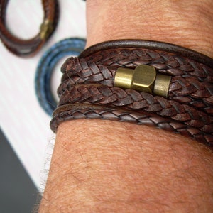 May include: A brown leather bracelet with a braided design and a brass clasp.