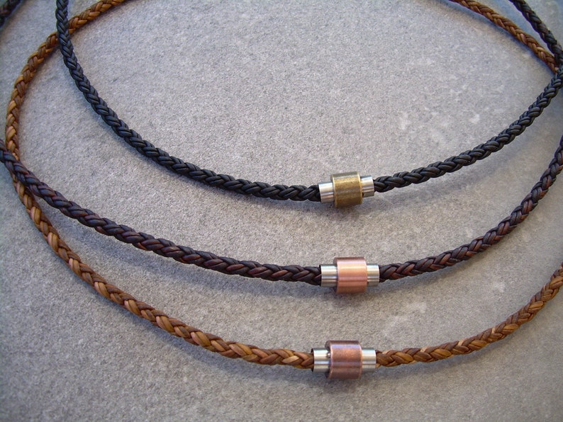 Peut inclure: Trois colliers en cuir tress&eacute; avec des accents de perles m&eacute;talliques. Les colliers sont de couleur marron, noir et marron clair. Les perles m&eacute;talliques sont argent&eacute;es, cuivr&eacute;es et en laiton.