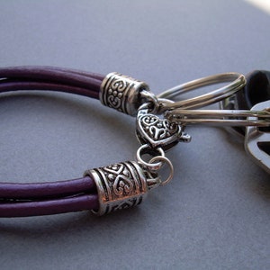 May include: A purple leather bracelet with silver metal beads and a silver key chain attached.