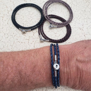 May include: Three leather bracelets with silver clasps. The bracelets are in black, brown, and blue.