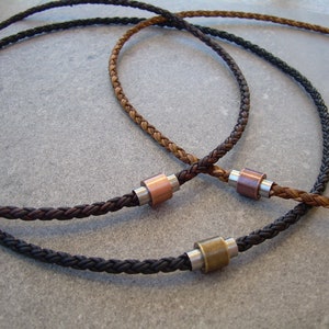 Peut inclure: Trois colliers en cuir tress&eacute; avec des fermoirs m&eacute;talliques. Les colliers sont marron, noir et une combinaison de marron et de noir.