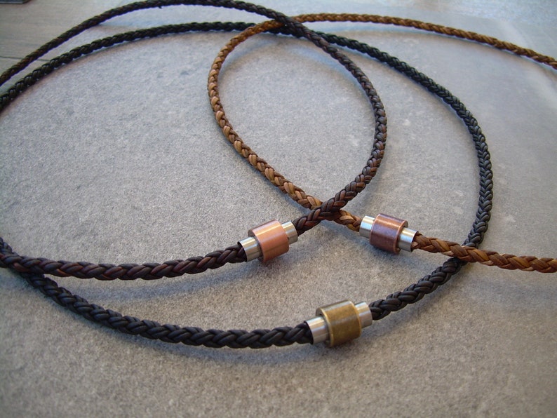 Peut inclure: Trois colliers en cuir tress&eacute; avec des fermoirs m&eacute;talliques. Les colliers sont marron, noir et une combinaison de marron et de noir.