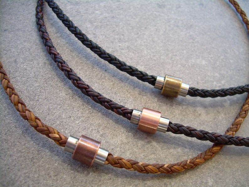 Peut inclure: Trois colliers en cuir tress&eacute; avec des perles m&eacute;talliques. Les colliers sont marron, noir et marron clair. Les perles sont argent&eacute;es, cuivr&eacute;es et en laiton.