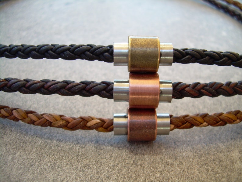 Peut inclure: Trois bracelets en cordon de cuir avec des fermoirs m&eacute;talliques. Les bracelets sont noir, marron et beige. Les fermoirs sont argent&eacute;s, en laiton et en cuivre.